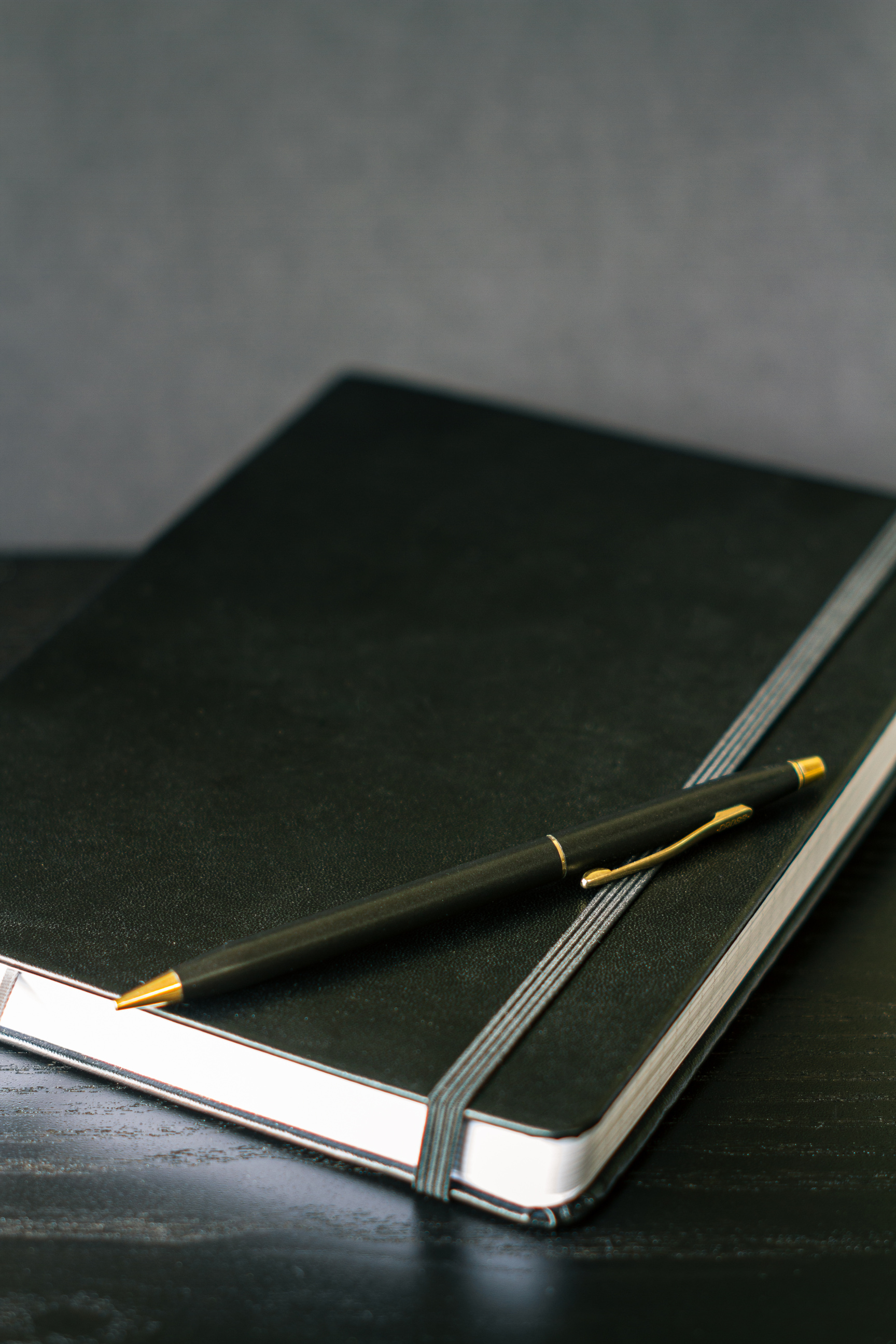 Black and Gold Pen on Black Notebook